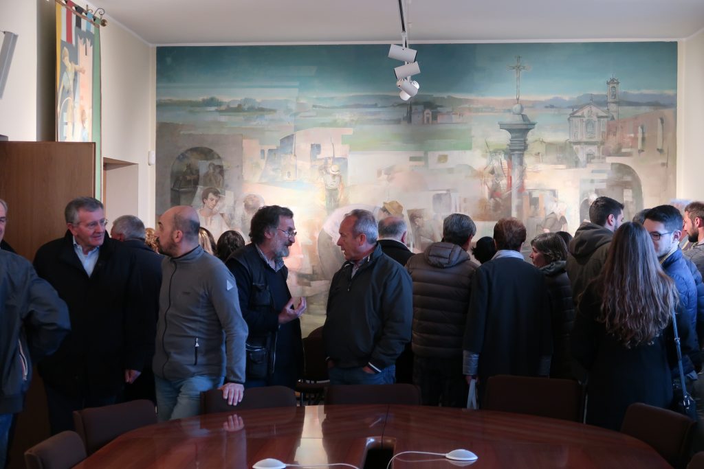 Pubblico nell'aula consigliare del comune di Fenegrò. Sullo sfondo, "Scene di vita agreste"; acrilico su tela - fotografia © Giancarlo Nicoli