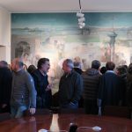 Pubblico nell’aula consigliare del comune di Fenegrò. Sullo sfondo, “Scene di vita agreste”; acrilico su tela – fotografia © Giancarlo Nicoli